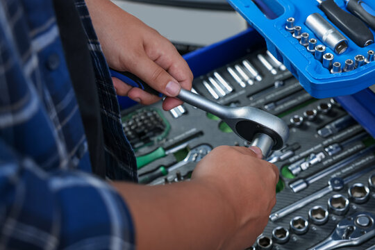 Auto mechanic with torque wrench at automobile repair shop, closeup