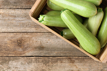 Crate with fresh zucchinis on wooden table, top view. Space for text