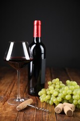 Corkscrew, corks, bottle of wine, glass and grapes on wooden table