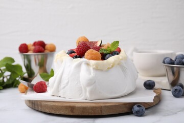 Pavlova cake (meringue dessert) with whipped cream, fresh berries and mint on white marble table, closeup