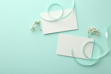 Flat lay composition with blank card, gypsophila flowers and ribbons on turquoise background. Space...