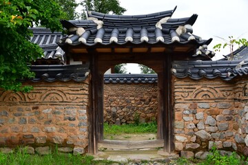 Hahoe village, Andong-si, Gyeongsangbuk-do, South Korea - August 3, 2020: Tile roof gate with dirt and stone wall at Byeongsanseowon Confucian Academy
