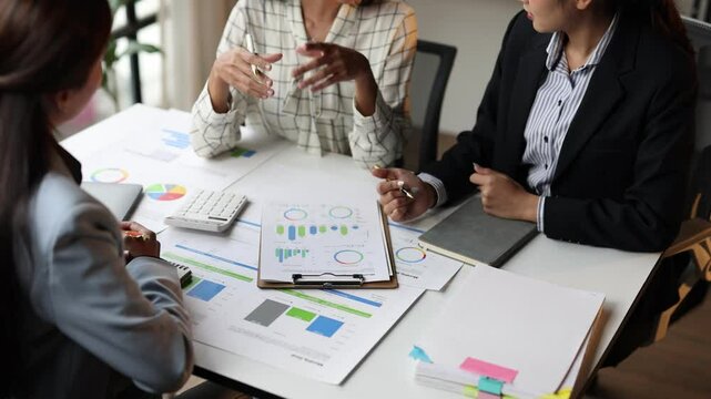 Business professional collaborating at a table filled with financial graph and chart, discussing strategies and planning. Meeting to discuss analysis financial situation and budget planning.