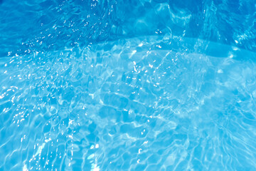 Blue water with ripples on the surface. Defocus blurred transparent blue colored clear calm water surface texture with splashes and bubbles. Water waves with shining pattern texture background.
