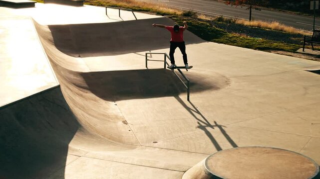Skateboarder performs boardslide at local skatepark during sunset