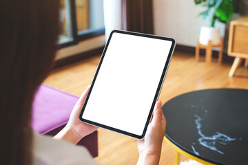 Mockup image of a woman holding digital tablet with blank desktop screen at home
