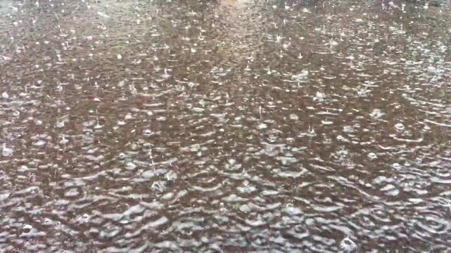 4k heavy rain drops falling into puddles on asphalt. Raindrop falling in rainy season. Large drops of rain on asphalt road, turning into large puddle, flooding street. Heavy rains caused floods.