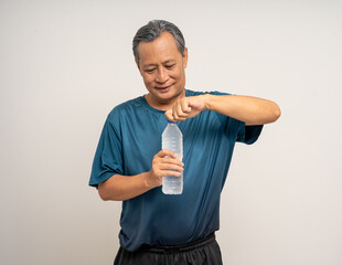 Senior asian old man with sportswear holding bottle of water and drinking on isolated white background. happy healthy fit and firm attractive sporty mature man standing pose exercise workout