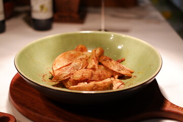 Fried potatoes in a green plate on a wooden table