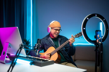 Professional Musician with condenser microphone and tablet for Mixing Mastering music. Music composer male composing a song with guitar and piano keyboard at digital Recording home studio