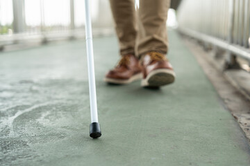 Obraz premium Young blind man walking in city with walking stick. Visually impaired man difficult to traveling on the road wearing sun glasses Cross the road cross the footbridge