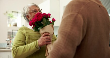 Senior, couple and happy for flowers in kitchen with surprise for celebration of anniversary, relationship and romance. Old man, woman and together in home with kiss for affection, bonding and love. - Powered by Adobe