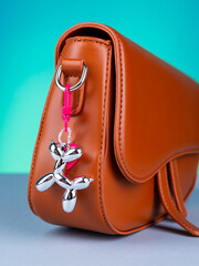 Close up of shiny dog ​​shaped keychain on trendy brown bag