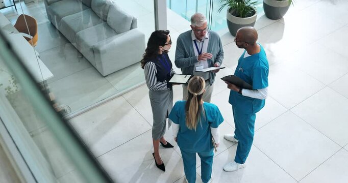 Doctors, group and discussion in lobby at hospital with paperwork, tablet and above for healthcare service. Clinic director, staff and team in scrum for meeting with documents, feedback or inspection