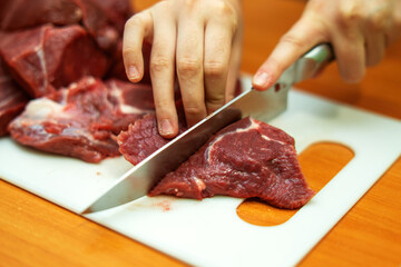 skilled hand expertly slices fresh beef into precise pieces, showcasing the art of butchery. The glistening meat reflects mastery and tradition in culinary craftsmanship