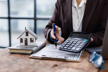 Pressing calculators, hand plans home refinance. House model, buy or rent, calculators on desk....