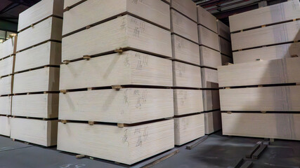 A stack of wood planks are piled high in a warehouse