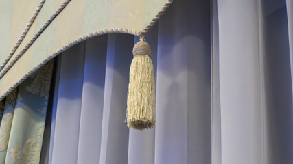 A white tassel hangs from a curtain