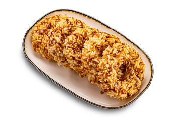 High angle view group of crispy homemade sweet rice crackers with cane sugar syrup in brown ceramic tray with dark edge isolated on white background with clipping path.