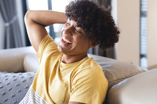 Laughing and relaxing on couch, young man enjoying time with diverse friends, at home