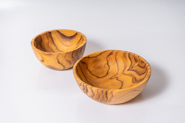 Two wooden bowls with a wood grain pattern. The bowls are placed on a white surface. The bowls have a rustic and natural appearance, which gives them a warm and inviting feel