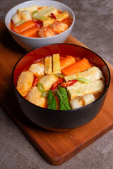 Steamboat is a soupy dish with fillings such as vegetables, seafood, eggs, meat, and noodles. a bowl of steamboat on a plank mat