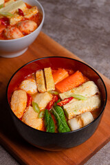 Steamboat is a soupy dish with fillings such as vegetables, seafood, eggs, meat, and noodles. a bowl of steamboat on a plank mat