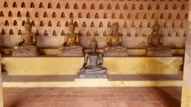 Dolly in shot to the old Buddha statue sitting in meditation Lotus pose in the courtyard of a Buddhist temple Wat Si Saket. Vientiane, Laos