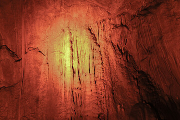 Naklejka premium Stalactites hanging from the vaults of the cave illuminated by artificial light