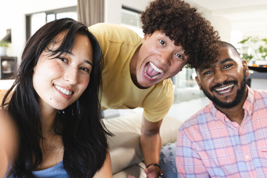 Smiling diverse friends hanging out at home, enjoying time together and having fun