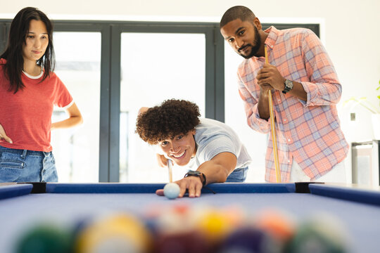 Playing pool, diverse friends enjoying leisure time together in relaxed setting, at home