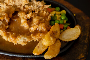 Sirloin steak fried in flour on a hot plate. served with steak sauce, potatoes, and peas. 