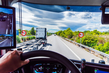 View from the driver's seat of a truck of traffic signs on the highway prohibiting overtaking by...