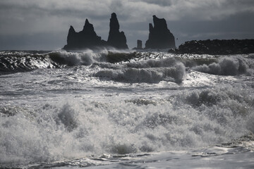 Large ocean waves at the Vik beach in Iceland with dark cliffs in the background