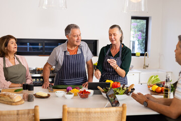 Cooking together, senior diverse friends preparing healthy meal in modern kitchen, at home