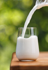 milk pouring into glass from jug on table