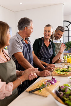 Preparing vegetables, senior diverse friends cooking together and enjoying conversation in kitchen,