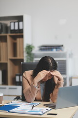 Portrait of tired young business Asian woman work with documents tax laptop computer in office....