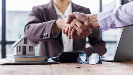 Lawyer shaking hands with a client making about documents, contracts, agreements, cooperation agreements with a female client at the lawyer's desk and a hammer at the table.
