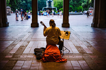 Street musician guitarist playing in archway tunnel late evening street lights slow motion