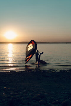 Man athlete comes out of the water with wing foil equipment.