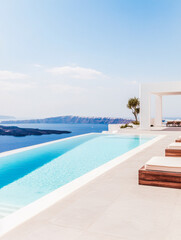 Fototapeta premium Stunning infinity pool at a modern villa overlooking the ocean with serene views in Santorini, Greece during a clear sunny day