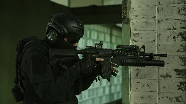 Special forces operator in black military outfit reloading his m4 assault rifle in an abandoned warehouse