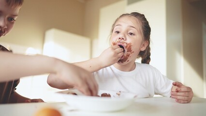 baby boy and girl eat chocolate. dirty little baby kids in the kitchen eating chocolate in the morning. happy family eating sweets kid dream concept. baby sweet dirty face eating chocolate cocoa