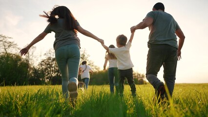 happy family running in the park in summer. mom and dad hold their son by the hands run throw up in...