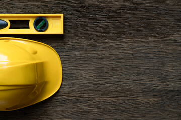 Yellow building level and helmets on the old wood table, engineering eqipment tool concept