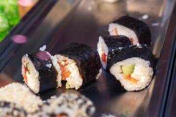 A detailed close up view of several sushi rolls beautifully arranged on a tray