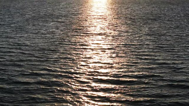 Pan up camera movement on arial shot flying across the lake towards the sunset coming behind the mountain. California, 4k, Drone