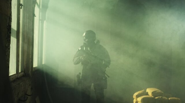 Special forces operator in black military gear and an m4 assault rifle in a room full of smoke