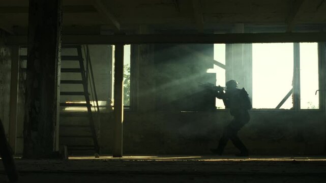 Silhouette of a soldier walking silently with his assault rifle in an abandoned building